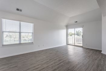 A room with wooden flooring and a window with blinds